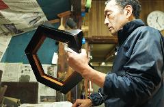 Use Premium Shark Skin and Traditional Lacquer to Craft a Masu Cup near Inuyama Castle A man in a workshop polishes a hexagonal wooden frame with a white cloth.