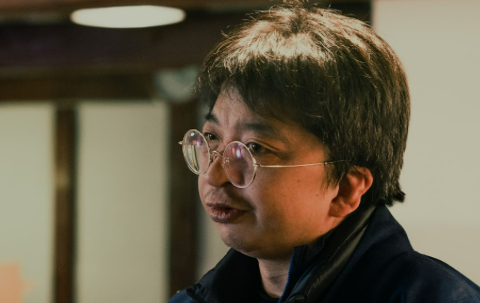 Kitakata Exclusive Sake Tasting Tour – Meet the Brewery President A close-up shot captures a man with glasses, his mouth slightly open as if speaking, with a blurred background.