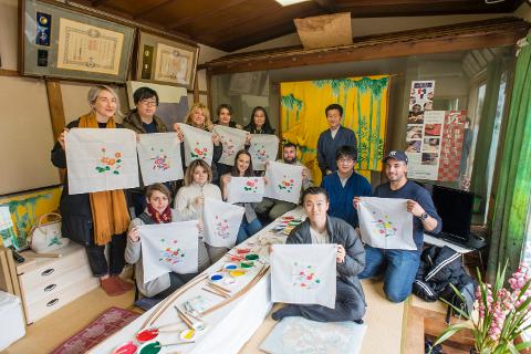 A group of people display their Nagoya Yuzen dyed cloths in a traditional Japanese room.