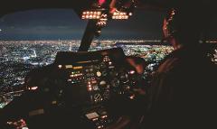 Exclusive 20-Minute Helicopter Ride Around Yokohama A pilot operates a helicopter's dashboard at night, overlooking a brightly lit cityscape.