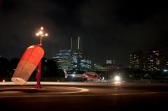 Exclusive 20-Minute Helicopter Ride Around Yokohama A helicopter is parked on a helipad at night, with a windsock in the foreground and city skyline in the background.