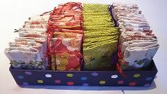 A polka-dotted tray holds neatly stacked pouches in three distinct patterns: floral-white, floral-red, and textured-green.