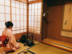 Geisha and Tea Ceremony! Experience traditional Japanese culture in Asakusa.(English Support Available) A woman in a kimono kneels on tatami mats in a room with shoji screens, participating in a traditional Japanese tea ceremony.