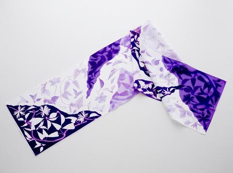 A purple and white floral-patterned scarf is lying on a white background.