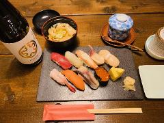 A Japanese meal featuring sushi, miso soup, and sake arranged on a wooden table.