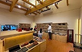 Experience 200 Years of Craftsmanship: Wajima Lacquerware Studio Tour (Visit a craftsman's home) This image shows the interior of a Wajima lacquerware studio, with visitors admiring displays of lacquerware products on shelves and counters.
