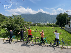Five cyclists pose in front of a scenic mountain view, celebrating their onsen town cycling tour.