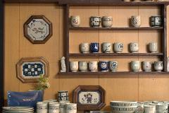 Ceramică și porțelan: Povești ale artizanilor din spatele meșteșugului A potter works on a spinning clay vessel, his hands shaping the material as he bends over the wheel.