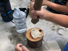 Washi Art, Draw a Picture While Making Washi Paper from Raw Materials in Tokyo's Countryside A child is pounding a pale substance with a wooden mallet into a wooden block next to a water bottle.