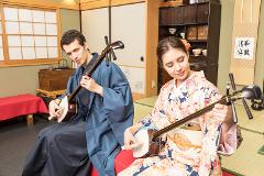 Play a Traditional Japanese String Instrument -- "Shamisen" A man and a woman in traditional Japanese attire play the shamisen in a serene setting.