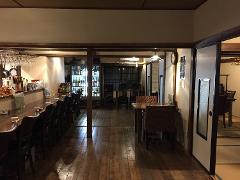 The image depicts a traditional Japanese restaurant interior with a long bar, wooden tables, chairs, and a glimpse into a tatami-mat room.