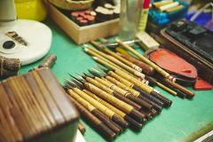 A collection of traditional Japanese calligraphy tools, including brushes, ink stones, and carving tools, are neatly arranged on a green surface.
