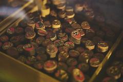 A close-up shot captures a wooden box filled with an assortment of small, round, hand-carved Japanese Hanko seals, each featuring intricate designs and red ink.