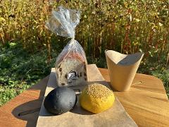 Explore the Local Morning Charm of Shiobara Onsen with a Satoyama Mini-Trek and Local Breakfast Delight A fresh breakfast of bread, a black bun, and a sesame bun is presented on a wooden table outdoors.