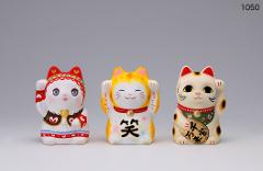 Three ceramic lucky cats, each with a raised paw, are displayed against a plain background.