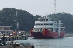 A red and white ferry, "Meon 2", approaches a dock with trees and a utility tower in the background.