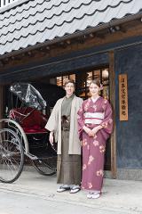 Asakusa Kimono Rental Plan - Choose From a Variety of Beautiful Kimonos A couple in traditional Japanese kimonos smiles in front of a building with a rickshaw beside them.