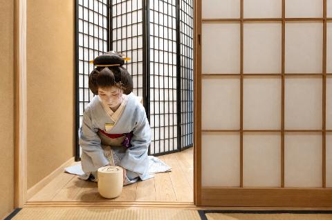 Geisha and Tea Ceremony! Experience traditional Japanese culture in Asakusa.(English Support Available) A woman in a kimono kneels on tatami mats in a room with shoji screens, participating in a traditional Japanese tea ceremony.