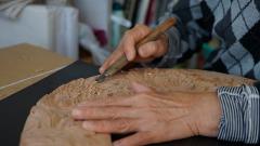 Visit Nikko's Craftsmanship Workshop to Experience Historic Techniques An artisan's hands carve intricate details into a wooden piece using a chisel.