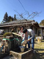 Two people are making paper by a well in a rural setting.