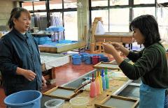 Two women are making handmade paper in a workshop.