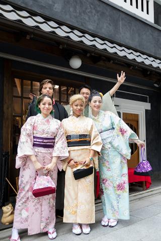 A group of five people in kimonos pose for a photo in front of a traditional Japanese building.
