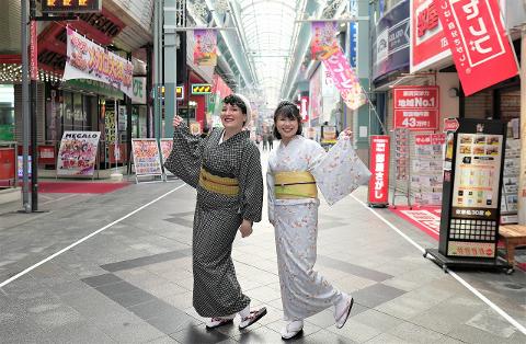 Nagoya Osu Cultural Walk in Kimono – Vintage Spots & Photo Map Two women in traditional kimonos pose in front of shops with Japanese signs and banners.