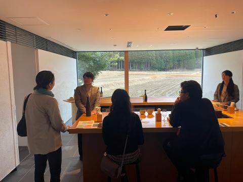 Kutani Gold Painting & Sake Tour – Komatsu Full-Day Package A group of people are having sake tasting and Kutani ware gold painting experience at a kiln with a beautiful landscape view.