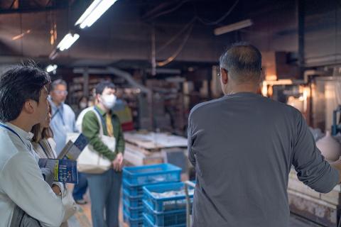 Pottery & Porcelain: Stories of the Artisans Behind the Craft A group of people on a tour look at artisans working in a pottery studio.