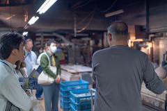 Pottery & Porcelain: Stories of the Artisans Behind the Craft A group of people on a tour look at artisans working in a pottery studio.