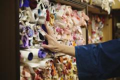 A person's hand touches rolls of fabric in a display, showcasing the vibrant colors and textures of a craft store.