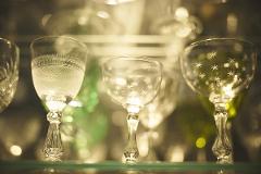 A close-up shot shows three vintage crystal glasses, two with intricate patterns and one adorned with star-like etchings, displayed on a shelf.