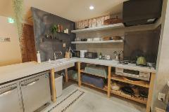 A well-organized kitchen features concrete countertops, light wood shelving, stainless steel appliances, and ample storage space with a rug on the floor.