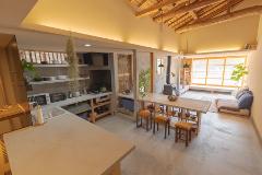 A well-lit, open-concept kitchen and living area with concrete floors, wood accents, and a high, beamed ceiling create a warm, inviting space.