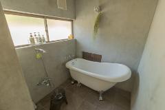 A charming bathroom with a freestanding white bathtub, gray walls, and natural light from a window, complemented by a shower fixture and subtle decor.